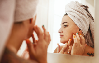 Mujer mirándose rostro con acné
